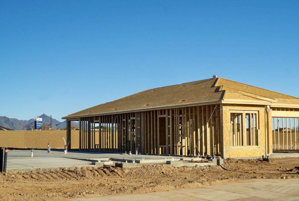 A framed house under construction and a concrete slab foundation with plumbing ready for framing